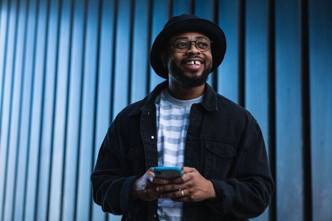 Positive Black hipster man using mobile phone