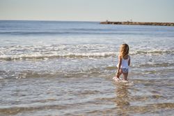 a little girl at the seashore entering the water