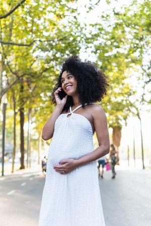 Smiling Black pregnant woman talking on smartphone