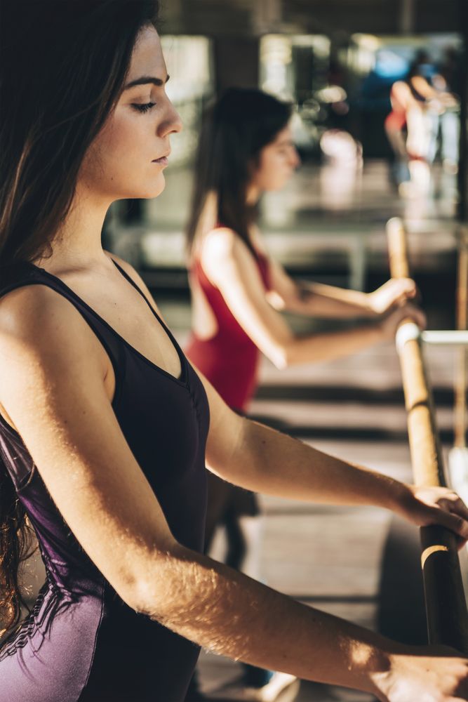 Side view of confident serious dancers practicing ballet in sunlight.