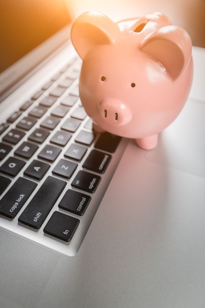 Piggy Bank Resting on Laptop Computer Keyboard.