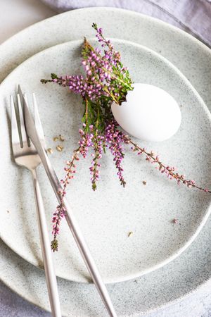 Top view of Easter table setting with egg and heather on grey plates