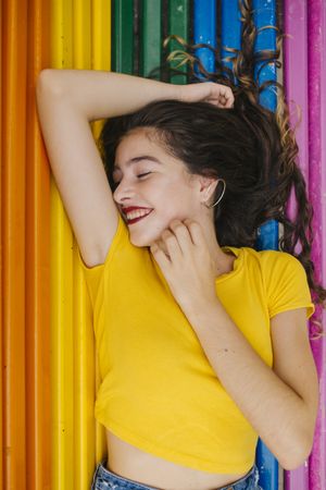 Cheerful woman lying down on rainbow bench back ground