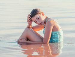 Teenage girl sitting in fresh water in sunny day