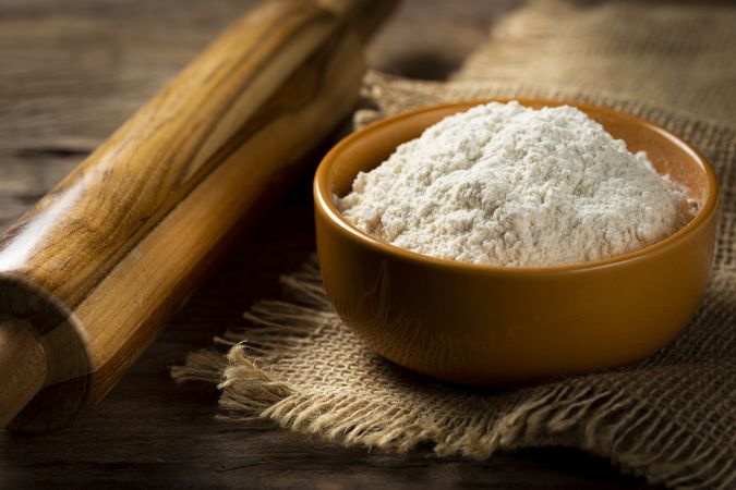 Bowl with wheat flour on the table.