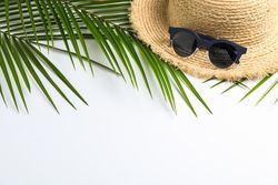 Composition with straw hat, sunglasses and palm leaves on blank background. Top view, space for text