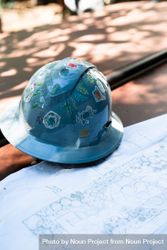 Hard hat decorated with stickers sitting on blue print 0LKoVb