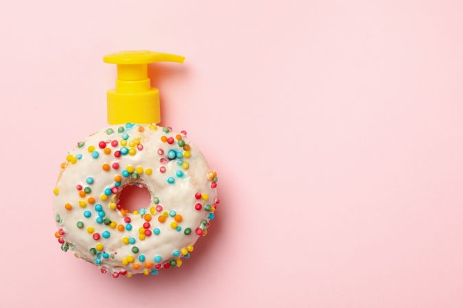 Tasty donut with dispenser on pink background
