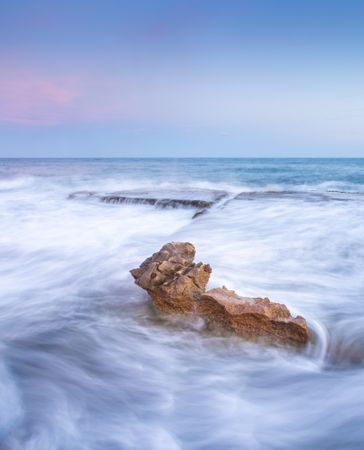 Amazing stones on shore near water and blue sky