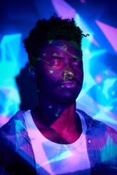 Calm Black man standing with eyes closed in neon lights