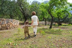 Faceless kids walking in verdant summer park