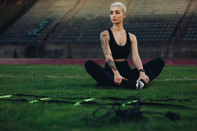 Fitness woman sitting in a track and field stadium doing workout