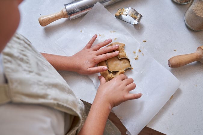 Kid making cookies with cutter