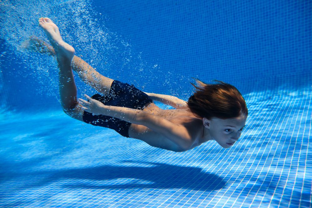 Kid in swimsuit diving into pool