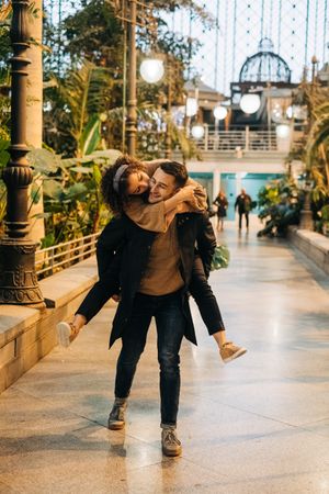 Man carrying happy girlfriend on back