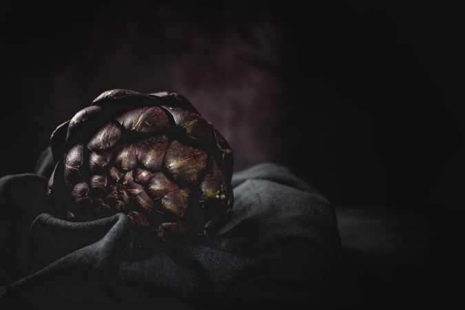 Fresh raw purple artichokes on dark background.