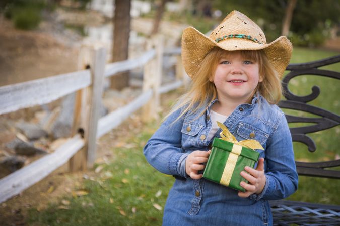 Young Girl Wearing Holiday Clothing Holding Christmas Gift Outside