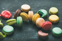 Assortment of multi-colored macaron pastries against a dark background, horizontal composition