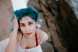 Gracious woman in sundress lying on back on parapet and reaching out for ocean