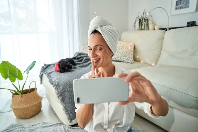 Cheerful woman demonstrating shh sign while taking on video call