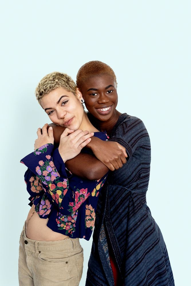 Photo of joyful females embracing dressed in casual jumpers