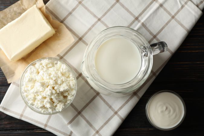 Fresh dairy products and towel on wooden background, top view
