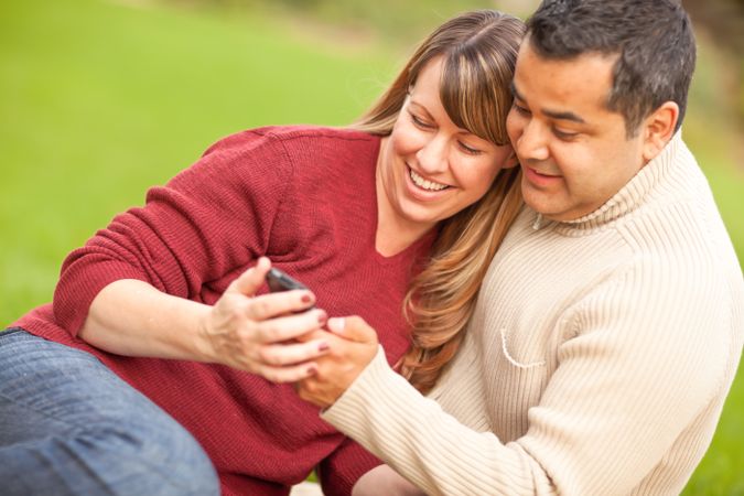 Couple Looking At Their Camera Phone in the Park