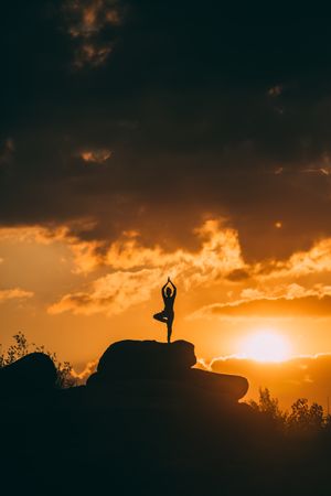 silhouette of woman doing yoga poses outdoors on a amazing sunset