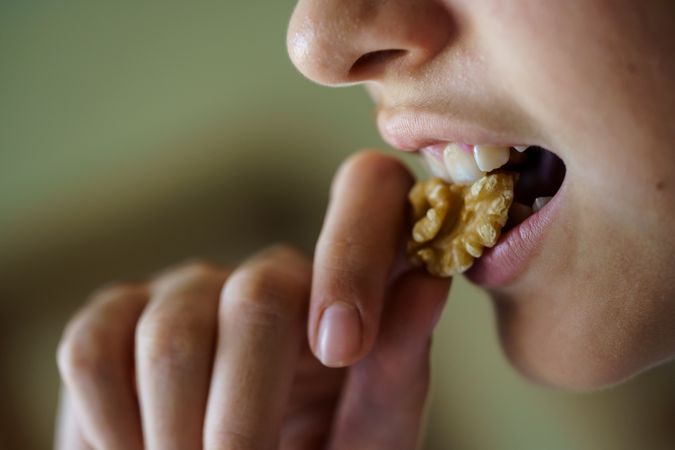 Side view of teenage girl eating healthy walnut