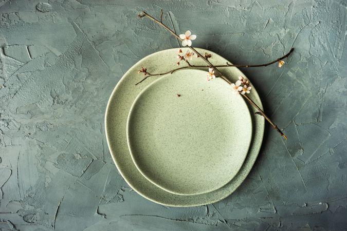 Top view of spring table setting with cherry blossom branch on green ceramic plate