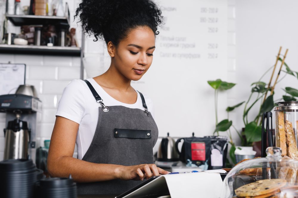 Barista looking down at tablet in coffee shop