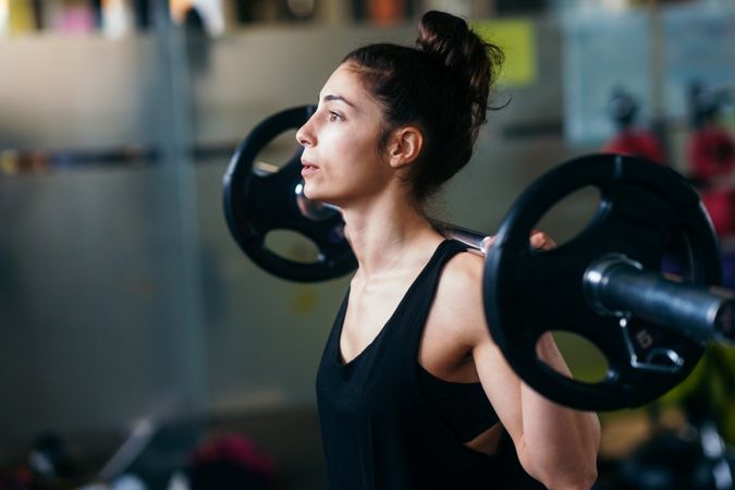 Athletic woman with barbell over her shoulders