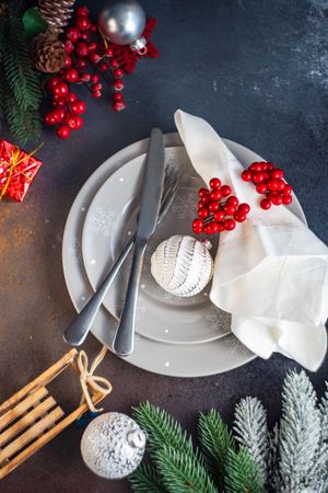 Top view of holiday table setting with grey plates and ornaments