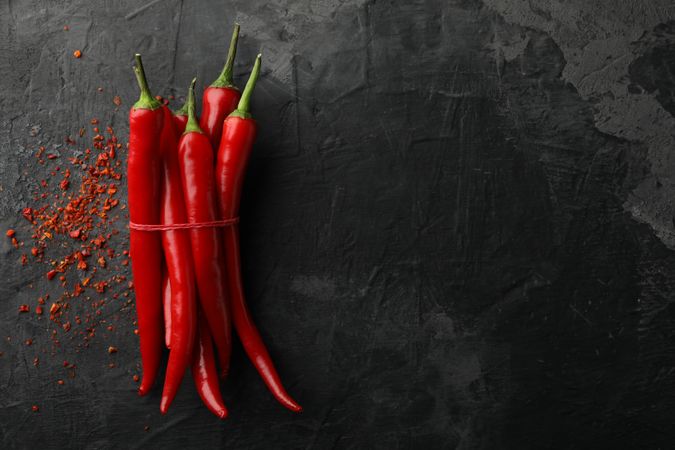 Chilli peppers on dark background, top view