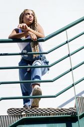 Female in denim overalls standing on skateboard on stairs