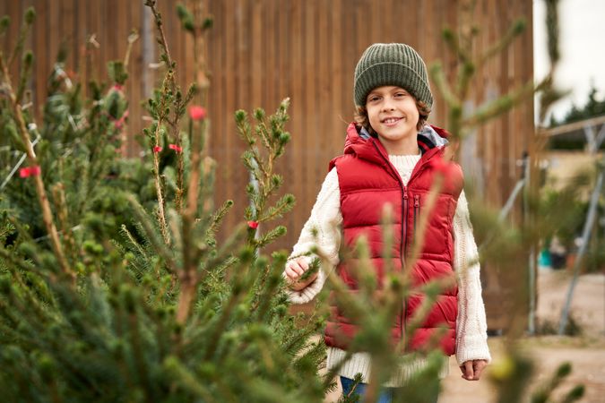 Cute kid in outerwear near Christmas tree