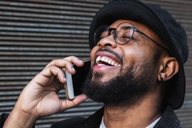 Laughing Black man talking smartphone