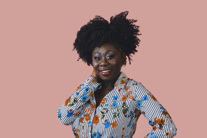 Portrait of happy Black woman smiling looking at camera with her hand on her neck