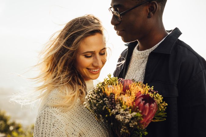 Young man gifting his girlfriend bouquet of flowers