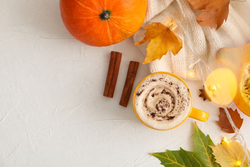 Composition with cup of pumpkin latte on light background
