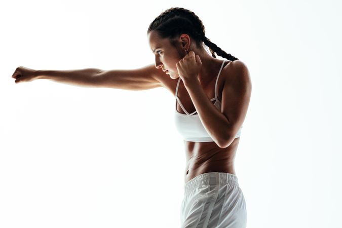 Female practicing boxing against light background