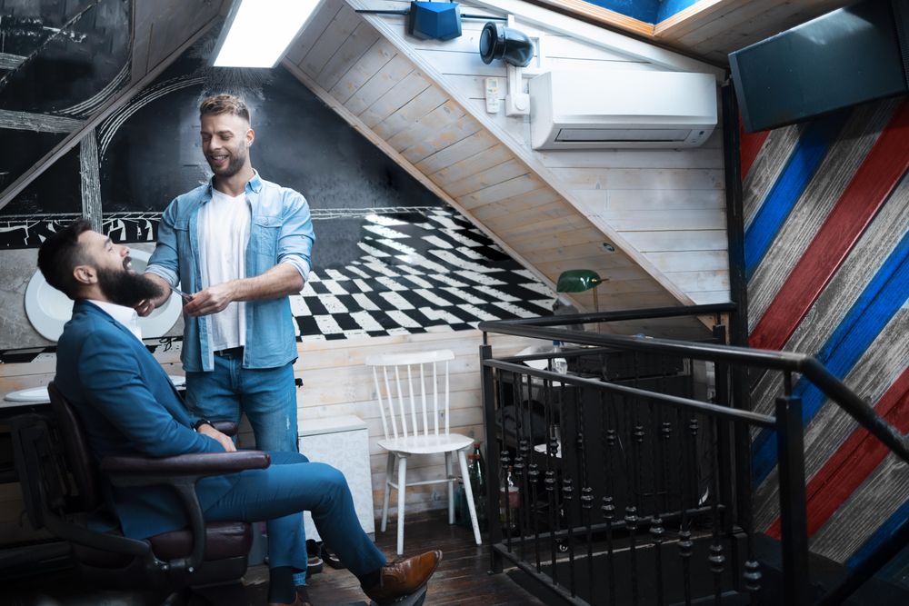 Man in blue suit having his beard trimmed in modern barbershop