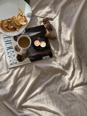 Bed with magazine, candles, breakfast and pinecones
