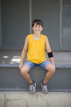 Casual dressed young smiling teen sitting outside, portrait