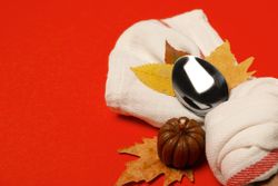 Spoon in towel, leaves and pumpkin on red background, space for text