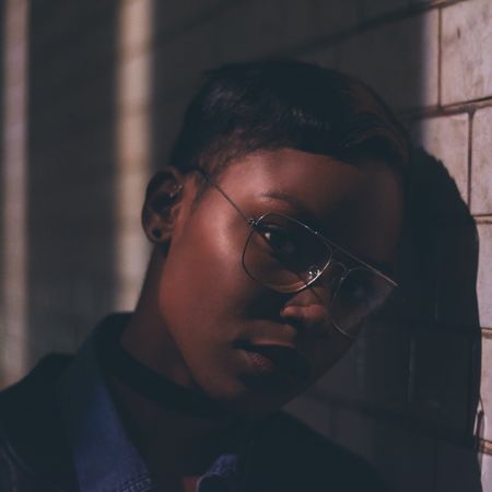 Head shot of woman in glasses leaning against wall