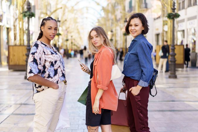 Three women looking back standing in shopping area