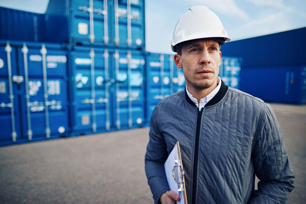 Man in hardhat on building site with clipboard