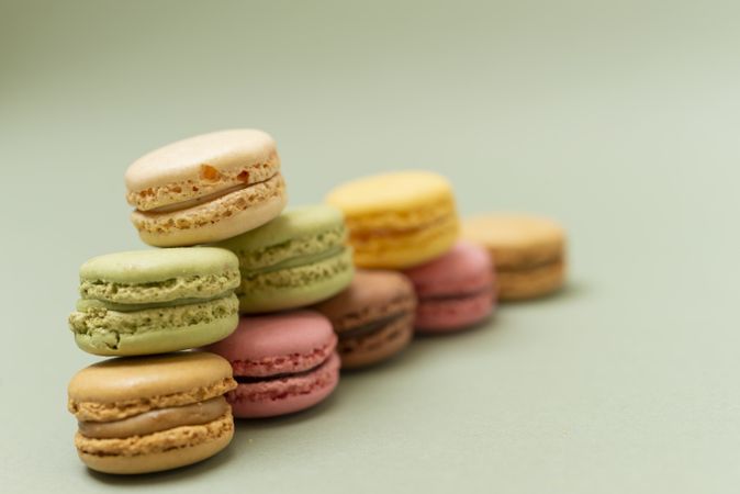 Pile of sweet pastel macaroons over a green background with copy space