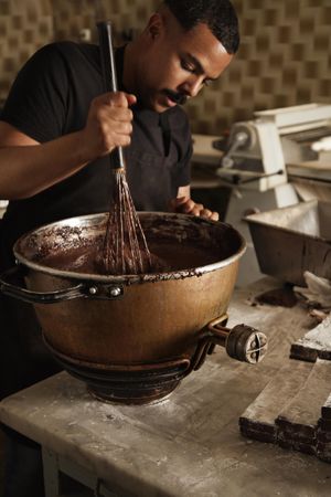 Professional chef whisking chocolate in large steel bowl